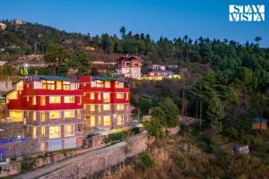 シムラーにあるStayVista at Nook - Elysium Estate 2 BR Cottage with Hill View, Lawnの灯火のある丘の上の家