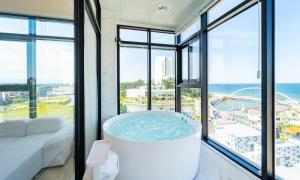 a large bath tub in a room with windows at Gangneung Skaria Poolvilla in Kangmun