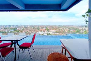 a table and chairs on a balcony with a view at RedLiving Star Apartemen Semarang - UMAKU Lantai 16 in Jomblang