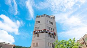 a tall white building with a sign on it at Busan Go House Pension in Busan
