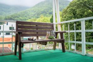 a wooden bench sitting on a balcony with a view at Geoje Ocean Love Pension in Geoje 