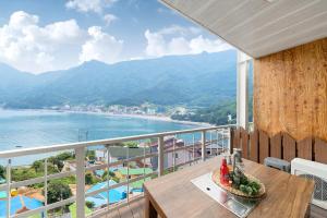 a balcony with a table and a view of the water at Geoje Ocean Love Pension in Geoje  +6 photos