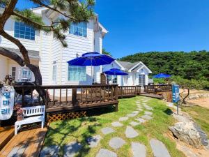 Una casa con una terraza con sombrillas azules. en Ganghwa ilmarae Pension, en Incheon