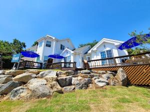 Una casa con sombrillas azules frente a una pared de roca. en Ganghwa ilmarae Pension, en Incheon