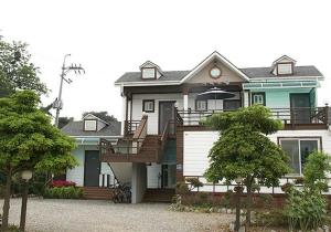 a large house with a porch and a staircase at Anmyeondo Jeonyeok Noeul Pension in Wŏlgoji +6 photos