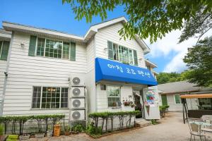 a white house with a blue sign on it at Gapyeong Morning Calm Pension in Gapyeong