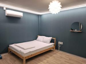 a bed in a room with a blue wall at Forest Caravan Pension Incheon in Incheon