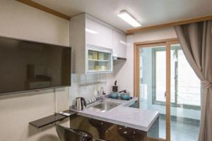 a kitchen with a sink and a large window at Ulsan Ghanjeolgot Suhocheonsa Pension in Nasa
