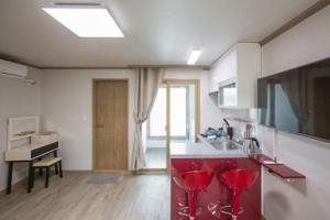 a kitchen with red bar stools and a sink at Ulsan Ghanjeolgot Suhocheonsa Pension in Nasa