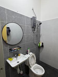 a bathroom with a toilet and a sink and a mirror at Meera Homestay in Melaka