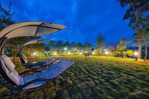 two chairs and an umbrella in a park at night at gangreung seuteieoseu in Kangmun