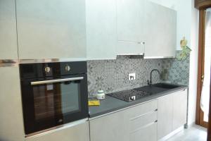 a kitchen with white cabinets and a black stove top oven at Luciana Apt - 3 min train to FCO Airport & Fiera in Fiumicino