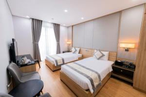 a hotel room with two beds and a chair at Herring Phu Quoc Hotel in Phu Quoc