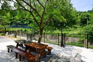 a picnic table and benches in front of a fence at Gapyeong La Vie En Rose Private Pension in Gapyeong