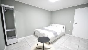 a white bedroom with a bed and a table at Gyeongju Zest57 Pension in Gyeongju +2 photos