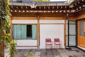 two red chairs sitting on the porch of a house at Luwa Private Pension in Jeonju