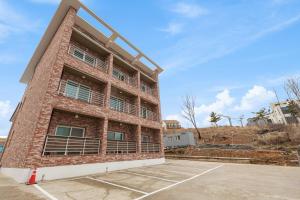 a brick building with a parking lot in front of it at Gangneung Marine Park Pension in Gangneung