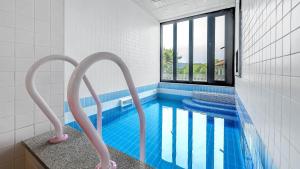 une salle de bains avec une piscine avec deux nageurs roses dans l'établissement Gyeonju Coo n eye kids poolvilla, à Gyeongju