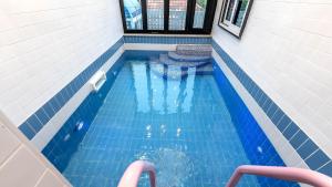 - une piscine dans une maison dotée de carrelage bleu dans l'établissement Gyeonju Coo n eye kids poolvilla, à Gyeongju