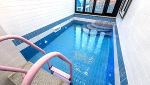 Une piscine bleue avec des escaliers y mène. dans l'établissement Gyeonju Coo n eye kids poolvilla, à Gyeongju