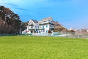 a large house with a green field in front of it at Gangneung Maison de Rose in Gangneung