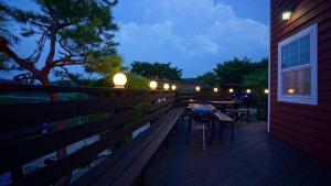 a wooden deck with a table and chairs on it at night at Buan Byeonsanbando Noeulbit Hill Pension in Buan +20 photos