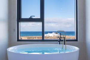 a bath tub in a bathroom with a view of the ocean at Donghae Staypear471 in Donghae