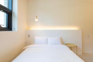 a white bed in a room with a window at Gangneung Gyeongpo 345 Pool Villa in Kyŏngp'o-mal