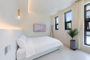 a white bedroom with a bed and a potted plant at Gangneung Gyeongpo 345 Pool Villa in Kyŏngp'o-mal