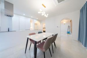 a white kitchen with a dining table and chairs at Gangneung Heonhwa-ro Pension in Gangneung