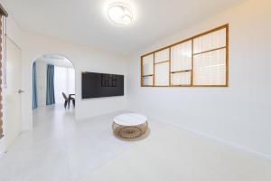 a white living room with a tv and a stool at Gangneung Heonhwa-ro Pension in Gangneung