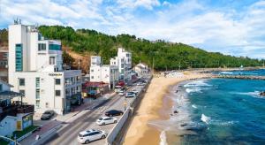 a city with cars parked on a beach next to the water at Donghae Adal Ocean Pension in Mukho-dong
