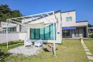 a house with two chairs and a swing at Gangneung Boni Stay in Ŭmji-mal