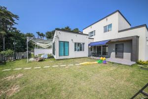 a white house with a yard with a toy at Gangneung Boni Stay in Ŭmji-mal