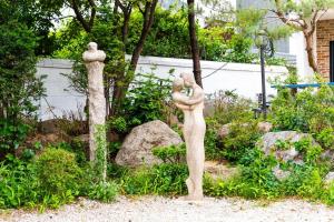 a statue of two statues of people in a garden at Ganghwa Bridge House in Incheon