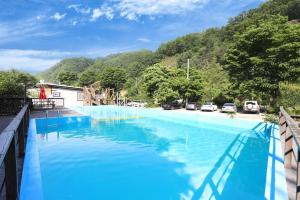 a large blue swimming pool with mountains in the background at Gapyeong Attirance Pension in Gapyeong