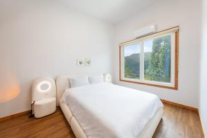 a white bedroom with a bed and a window at Yangpyeong Forest Live Pension in Yangpyeong