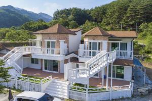 a large house with white balconies and a car at Gangneung Chunja Yeoinsook in Gangneung