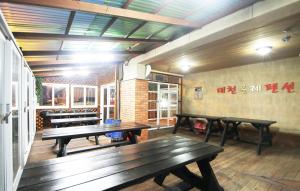 a patio with benches and tables in a building at Daecheon Ole Pension in Boryeong