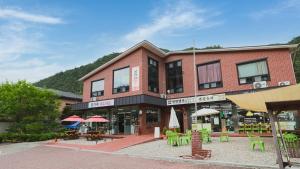 a brick building with tables and chairs and umbrellas at Gangwon Mountain Bnb in Wonju