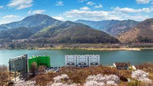 a building next to a body of water with mountains at Gapyeong River Wave Pool Villa in Gapyeong