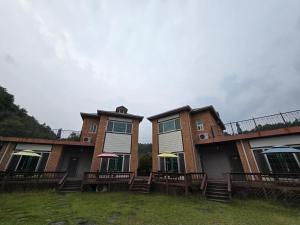 two buildings with tables and umbrellas in a yard at Dolmadang Cheongsu Pension in Mungyeong +3 photos