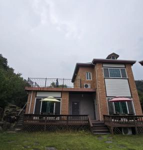 a house with a balcony with two umbrellas on it at Dolmadang Cheongsu Pension in Mungyeong