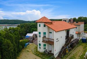 a white building with an orange roof with a balcony at Pension 1830 in Taean