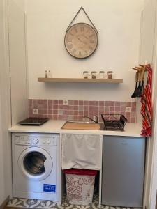 a kitchen with a washing machine and a clock on the wall at La Petite Vernoelle in Prémilhat