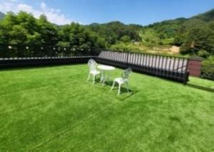 two chairs and a table on a lawn at Gapyeong House 2 71 Pension in Kŏjŏbi