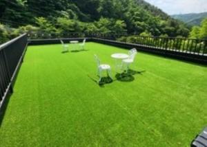 a balcony with green grass and white chairs on it at Gapyeong House 2 71 Pension in Kŏjŏbi +4 photos