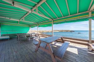 a wooden deck with picnic tables and the ocean at Gyeongju Nadeuli Pension in Gyeongju +8 photos