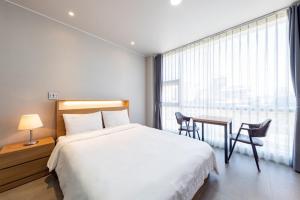 a bedroom with a bed and a desk and a window at Gangneung Gyeongpodae Villa in Kangmun