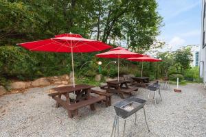 a group of picnic tables with red umbrellas at Sokcho White Lighthouse Pension in Sokcho